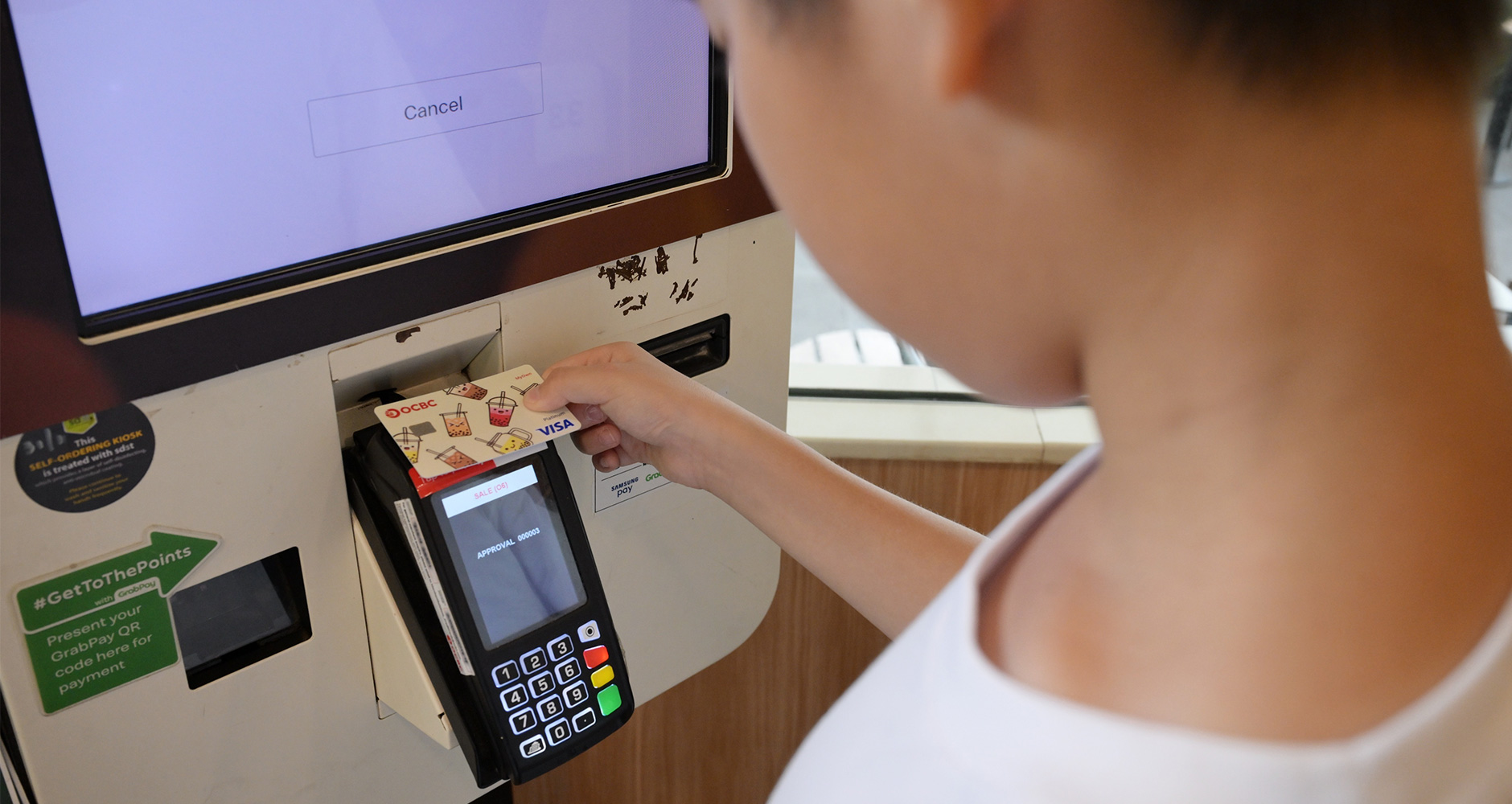 A child using an OCBC MyOwn debit card to make a payment.